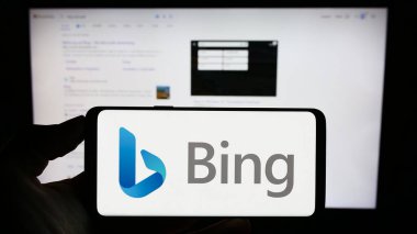 Stuttgart, Almanya - 09-22-2023: İnternet arama motoru logosu olan cep telefonu sahibi kişi Microsoft Bing, iş sayfasının önünde ekranda. Telefon ekranına odaklan.
