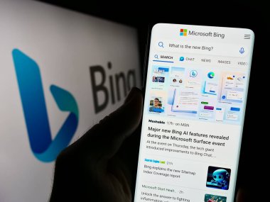 Stuttgart, Almanya - 09-22-2023: İnternet arama motoru Microsoft Bing 'in web sitesi olan cep telefonu sahibi kişi iş logosu önünde ekranda. Telefon ekranının merkezine odaklan.