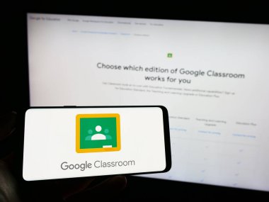 Stuttgart, Almanya - 09-23-2023: Harmanlanmış öğrenme platformunun logosuna sahip cep telefonu sahibi kişi web sayfasının önünde ekranda. Telefon ekranına odaklan.