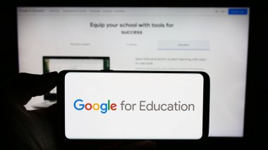 Stuttgart, Almanya - 09-23-2023: İş sayfası önündeki ekranda yazılım ürünü Google for Education 'ın logosunun bulunduğu cep telefonu sahibi kişi. Telefon ekranına odaklan.
