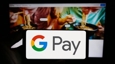Stuttgart, Almanya - 09-23-2023: İnternet sitesi önünde üzerinde mobil ödeme servisi Google Pay logosu bulunan akıllı telefon sahibi kişi. Telefon ekranına odaklan.