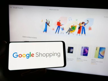 Stuttgart, Almanya - 09-23-2023: İnternet sitesinin önünde üzerinde ürün arama platformu logosu bulunan akıllı telefon sahibi kişi. Telefon ekranına odaklan.