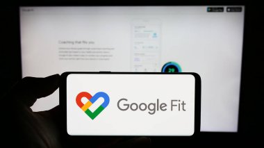 Stuttgart, Almanya - 09-23-2023: İş sayfasının önündeki ekranda sağlık izleme yazılımı Google Fit logosu olan cep telefonu sahibi kişi. Telefon ekranına odaklan.