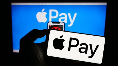 Stuttgart, Almanya - 09-23-2023: Cep telefonunda Apple Pay adlı mobil ödeme servisi logosu bulunan kişi iş sayfasının önünde ekranda. Telefon ekranına odaklan.