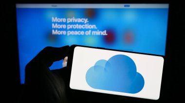 Stuttgart, Almanya - 09-23-2023: İş sayfasının önünde ekranda Apple iCloud 'un amblemi olan cep telefonu sahibi kişi. Telefon ekranına odaklan.