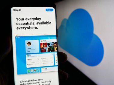 Stuttgart, Almanya - 09-23-2023: Bulut depolama platformu Apple iCloud 'un web sayfası olan cep telefonunu logonun önünde tutan kişi. Telefon ekranının merkezine odaklan.