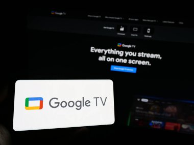 Stuttgart, Almanya - 09-23-2023: İş sayfası önündeki ekranda Google TV hizmeti üzerinde video logosu olan kişi. Telefon ekranına odaklan.