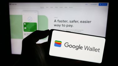 Stuttgart, Almanya - 09-23-2023: İnternet sitesinin önündeki ekranda dijital cüzdan uygulaması Google Cüzdan logosuna sahip akıllı telefonu tutan kişi. Telefon ekranına odaklan.