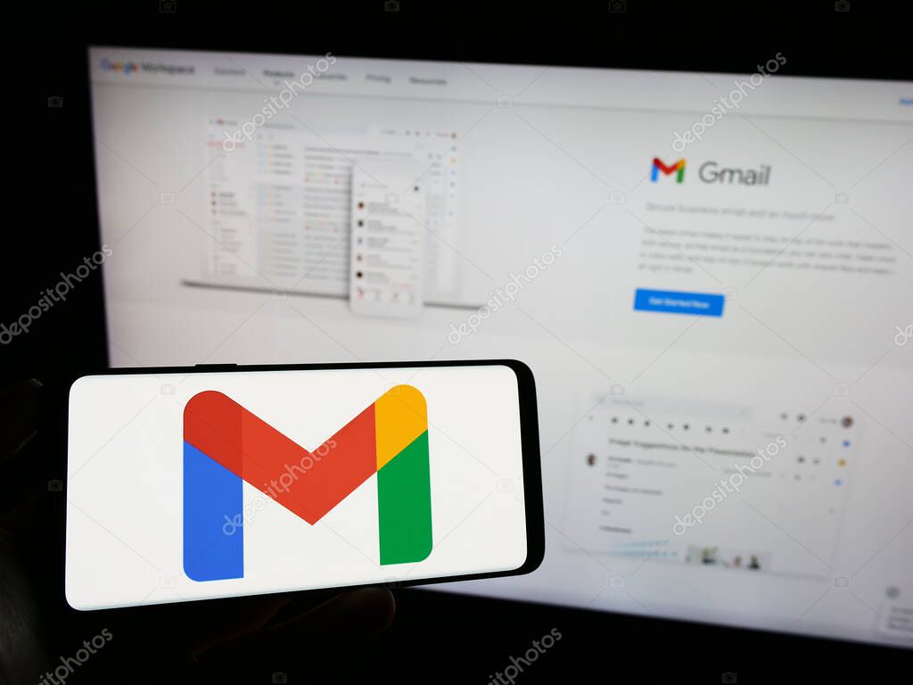 Stuttgart, Germany - 09-23-2023: Person holding cellphone with logo of email service Google Gmail on screen in front of company webpage. Focus on phone display.