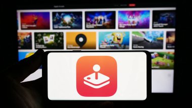 Stuttgart, Almanya - 09-23-2023: Web sitesinin önünde ekranda Apple Arcade video oyunu platformunun logosuna sahip akıllı telefonu tutan kişi. Telefon ekranına odaklan.