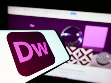 Stuttgart, Almanya - 09-23-2023: İnternet geliştirme yazılımı logosu olan cep telefonu Adobe Dreamweaver iş sitesinin önünde ekranda. Telefon ekranının merkezine odaklan.