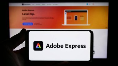 Stuttgart, Almanya - 09-23-2023: Grafik tasarım yazılımı Adobe Express 'in logosu olan akıllı telefonu web sitesinin önünde tutan kişi. Telefon ekranına odaklan.