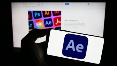 Stuttgart, Almanya - 09-23-2023: Hareket grafik yazılımı logosu olan cep telefonu sahibi kişi Adobe After Effects web sayfasının önünde ekranda. Telefon ekranına odaklan.