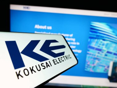 Stuttgart, Almanya - 09-24-2023: Japon şirketi Kokusai Electric Corporation 'ın logosunun yer aldığı cep telefonu iş sitesinin önünde ekranda. Telefon ekranının merkezine odaklan.