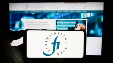 Stuttgart, Almanya - 09-24-2023: Cep telefonunda İsveçli mali düzenleyici Finansinspektionen logosu olan kişi web sayfasının önünde ekranda. Telefon ekranına odaklan.