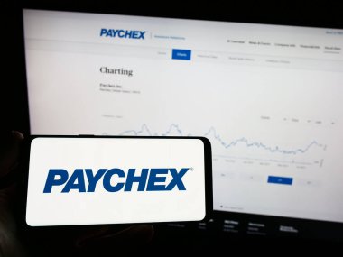 Stuttgart, Almanya - 08-06-2023: Amerikan dış kaynak şirketi Paychex Inc. 'in logosunun bulunduğu cep telefonu web sayfasının önünde ekranda. Telefon ekranına odaklan.