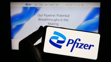 Stuttgart, Almanya - 08-06-2023: İnternet sitesi önünde ekranda ABD 'li ilaç şirketi Pfizer Inc.' in logosunu taşıyan kişi. Telefon ekranına odaklan.