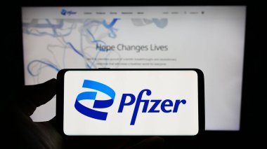Stuttgart, Almanya - 08-06-2023: ABD 'li ilaç şirketi Pfizer Inc.' in logosuyla cep telefonu sahibi kişi iş sayfası önünde ekranda. Telefon ekranına odaklan.