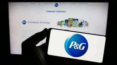 Stuttgart, Almanya - 08-06-2023: ABD 'li şirket The Procter Gamble Company' nin logosunu elinde tutan kişi web sitesinin önünde ekranda. Telefon ekranına odaklan.