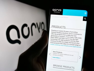 Stuttgart, Almanya - 08-06-2023: ABD 'li yarı iletken şirket Qorvo Inc.' in web sitesi ile akıllı telefon sahibi kişi logonun önünde ekranda. Telefon ekranının merkezine odaklan.