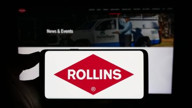 Stuttgart, Almanya - 08-07-2023: İnternet sitesinin önünde ekranda ABD 'li haşere kontrol şirketi Rollins Inc.' in logosuna sahip akıllı telefonu tutan kişi. Telefon ekranına odaklan.