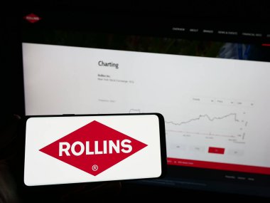 Stuttgart, Almanya - 08-07-2023: Amerikan haşere kontrol şirketi Rollins Inc. 'in logosunun bulunduğu cep telefonu web sayfasının önünde ekranda. Telefon ekranına odaklan.