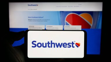 Stuttgart, Almanya - 08-08-2023: ABD 'li havayolu şirketi Southwest Airlines Co' nun logosuyla akıllı telefon sahibi kişi web sitesinin önünde ekranda. Telefon ekranına odaklan.