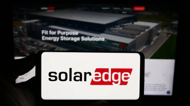 Stuttgart, Almanya - 08-08-2023: İsrailli SolarEdge Technologies Inc. şirketinin logosunu elinde tutan kişi web sitesinin önünde ekranda. Telefon ekranına odaklan.
