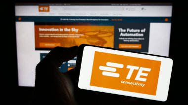 Stuttgart, Almanya - 08-09-2023: İsviçreli TE Connectivity Ltd. şirketinin logosuyla cep telefonu sahibi kişi iş sayfasının önünde ekranda. Telefon ekranına odaklan.