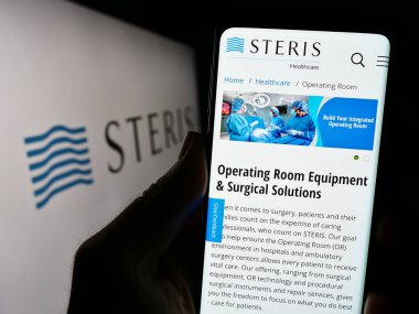 Stuttgart, Almanya - 08-09-2023: Tıbbi ekipman şirketi Steris plc 'nin web sitesi ile logo önünde akıllı telefon tutan kişi. Telefon ekranının merkezine odaklan.
