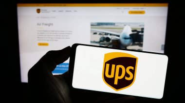 Stuttgart, Almanya - 08-11-2023: Amerikan şirketi United Parcel Service Inc. 'in logosunun bulunduğu cep telefonu web sayfası önünde ekranda. Telefon ekranına odaklan.