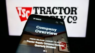 Stuttgart, Germany - 08-11-2023: Mobile phone with webpage of US retail business Tractor Supply Company on screen in front of business logo. Focus on top-left of phone display. clipart