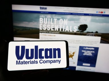 Stuttgart, Almanya - 08-12-2023: ABD 'li Vulcan Materyal Şirketi' nin logosunu elinde tutan kişi web sitesinin önünde ekranda. Telefon ekranına odaklan.