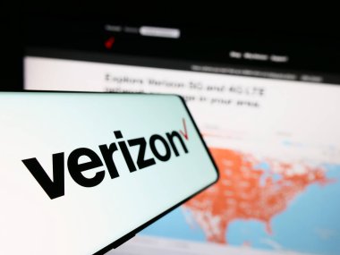Stuttgart, Almanya - 08-12-2023: Amerikan Verizon Communications Inc. şirketinin logosuna sahip akıllı telefon, iş dünyasının web sitesi önünde ekranda. Telefon ekranının soluna odaklan.