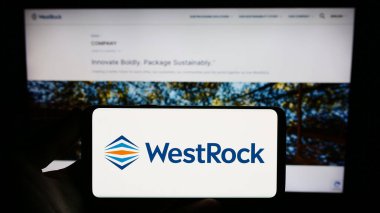 Stuttgart, Almanya - 08-12-2023: ABD ambalaj şirketi WestRock Company 'nin logosunu elinde tutan kişi web sitesinin önünde ekranda. Telefon ekranına odaklan.