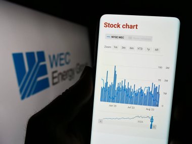 Stuttgart, Almanya - 08-12-2023: ABD 'li kamu hizmetleri şirketi WEC Energy Group Inc.' nin web sitesi ile cep telefonu sahibi kişi logo önünde ekranda. Telefon ekranının merkezine odaklan.