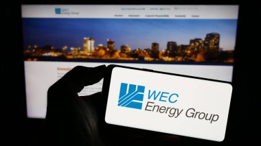 Stuttgart, Almanya - 08-12-2023: Web sitesi önünde ekranda ABD 'li kamu hizmeti şirketi WEC Energy Group Inc.' nin logosunu taşıyan kişi. Telefon ekranına odaklan.