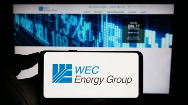 Stuttgart, Almanya - 08-12-2023: ABD 'li kamu hizmetleri şirketi WEC Energy Group Inc.' in logosuyla cep telefonu sahibi kişi iş sayfası önünde ekranda. Telefon ekranına odaklan.