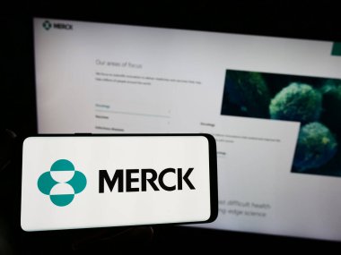Stuttgart, Almanya - 08-13-2023: Web sitesi önünde ekranda ABD 'li ilaç şirketi Merck Co. Inc.' nin logosunun bulunduğu akıllı telefonu tutan kişi. Telefon ekranına odaklan.