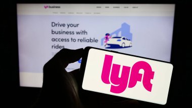 Stuttgart, Almanya - 08-13-2023: ABD 'li hareketlilik şirketi Lyft Inc.' in logosuyla cep telefonu sahibi kişi iş sayfasının önünde ekranda. Telefon ekranına odaklan.