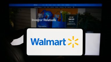 Stuttgart, Almanya - 08-13-2023: ABD 'li perakende şirketi Walmart Inc.' in logosuyla cep telefonu sahibi kişi iş sayfasının önünde ekranda. Telefon ekranına odaklan.