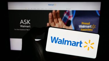 Stuttgart, Almanya - 08-13-2023: ABD 'li perakende şirketi Walmart Inc.' in logosuyla akıllı telefon sahibi kişi web sitesinin önünde ekranda. Telefon ekranına odaklan.