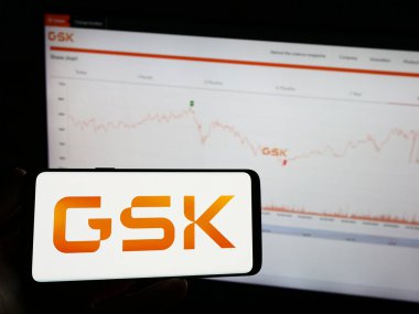 Stuttgart, Almanya - 08-13-2023: İngiliz ilaç şirketi GSK plc 'nin logosunun bulunduğu cep telefonu sahibi kişi iş sayfasının önünde ekranda. Telefon ekranına odaklan.