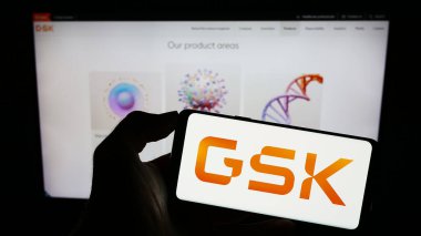 Stuttgart, Almanya - 08-13-2023: İngiliz ilaç şirketi GSK plc 'nin logosunun bulunduğu cep telefonu sahibi kişi iş sayfasının önünde ekranda. Telefon ekranına odaklan.