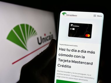Stuttgart, Almanya - 08-13-2023: İspanyol bankacılık şirketi Unicaja Banco S.A. 'nın internet sayfası olan cep telefonu logosu önünde ekranda. Telefon ekranının merkezine odaklan.