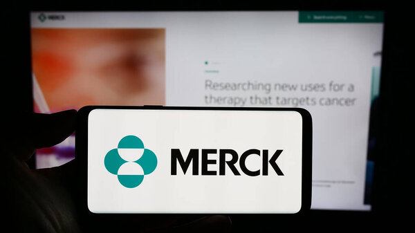 Stuttgart, Germany - 08-13-2023: Person holding mobile phone with logo of American pharmaceutical company Merck Co. Inc. on screen in front of web page. Focus on phone display.