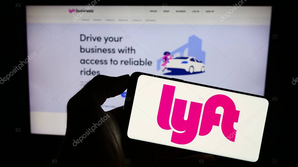 Stuttgart, Germany - 08-13-2023: Person holding cellphone with logo of US mobility company Lyft Inc. on screen in front of business webpage. Focus on phone display.
