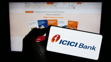 Stuttgart, Germany - 08-13-2023: Person holding cellphone with logo of Indian financial company ICICI Bank Limited on screen in front of business webpage. Focus on phone display. clipart