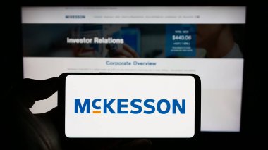 Stuttgart, Almanya - 08-13-2023: ABD 'li ilaç şirketi McKesson Corporation' ın logosunu elinde tutan kişi web sitesinin önünde ekranda. Telefon ekranına odaklan.