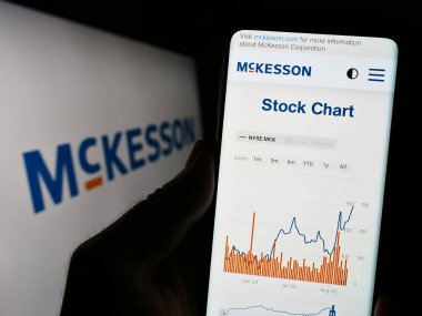 Stuttgart, Almanya - 08-13-2023: ABD 'li ilaç şirketi McKesson Corporation' ın internet sayfası ile cep telefonu tutan kişi logolu ekranda. Telefon ekranının merkezine odaklan.